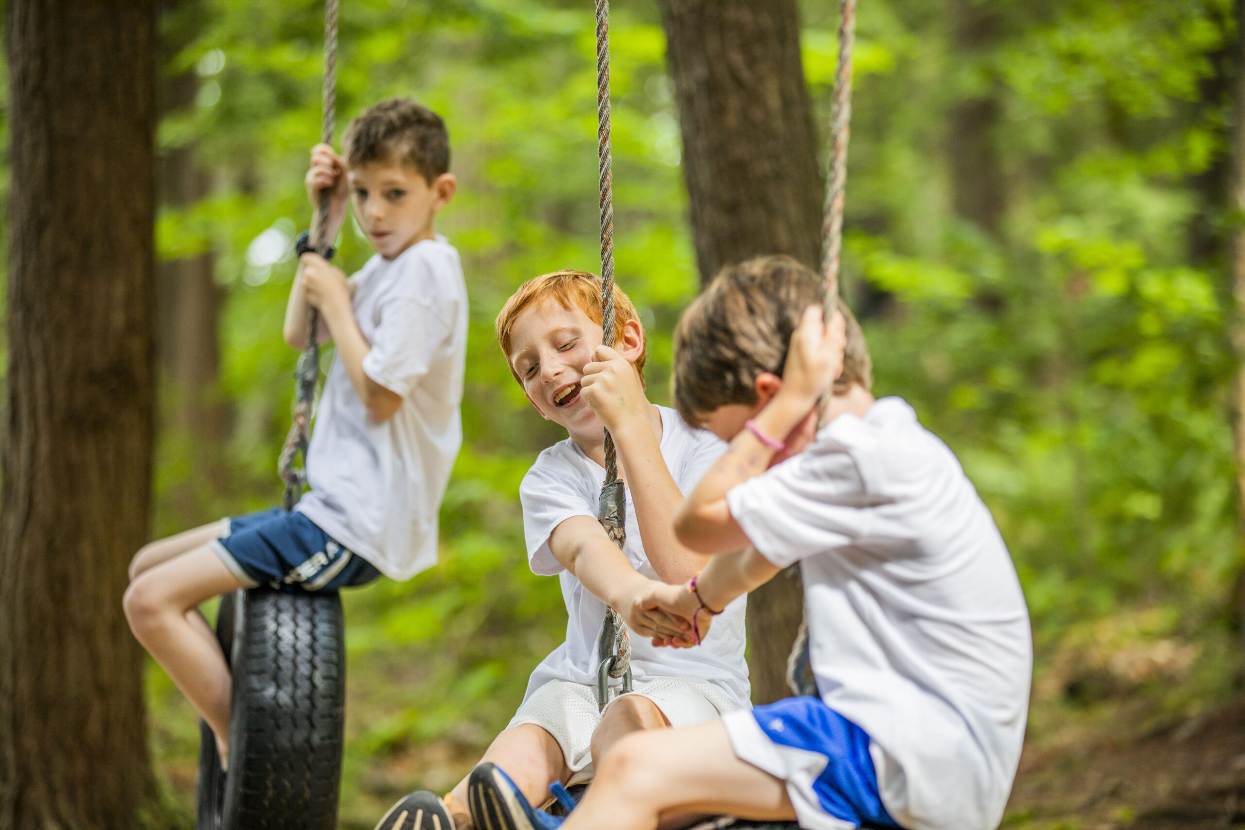 A camper building confidence on the high ropes adventure course at Kamp Kohut in Oxford, Maine.