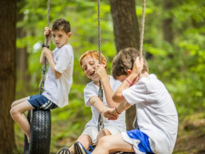 A camper building confidence on the high ropes adventure course at Kamp Kohut in Oxford, Maine.